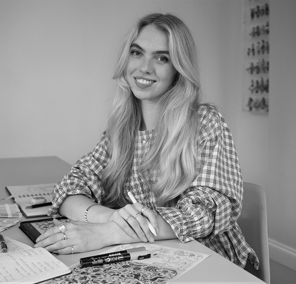 Black and white portrait of martha with her sketch pens and books infront of her on a table