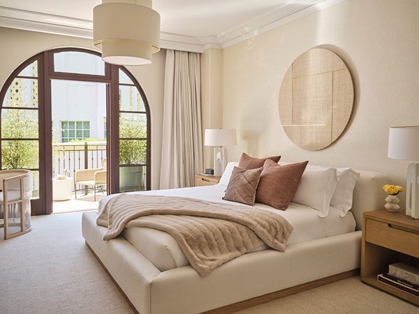 Residence bedroom with bed in the foreground and windows opening up to terrace open