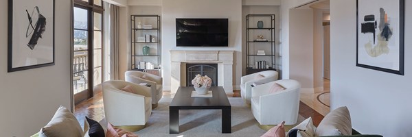 The Maybourne Beverly Hills Residence sitting room with white furniture and a vase of pink flowers on the coffee table